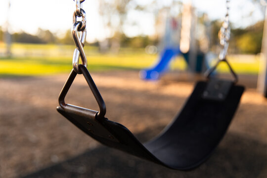 swing at a playground with other playground equipment out of focus in background