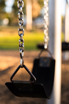 sling swing seat hanging off metal chains at a playground