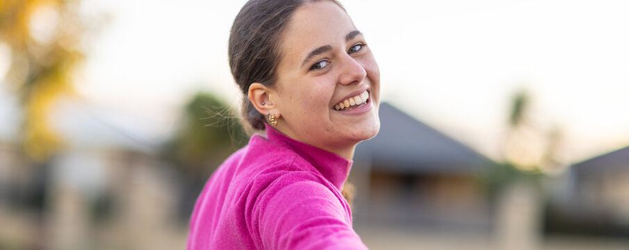 head and shoulders of teen girl looking back towards camera over her shoulder