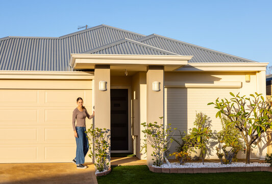facade of suburban house with young woman near portico