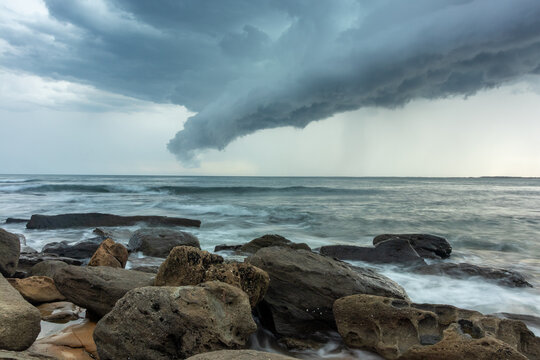 Storm clouds over ocean with rocky shoreline and waves