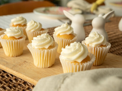 Mini cupcakes with white icing on wooden board with easter table decorations
