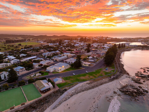 Aerial view of a brilliant sunset sky over a coastal town and sandy beach