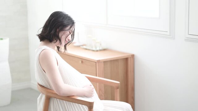 [スローモーション]笑顔でお腹に手を添える日本人女性の妊婦さん、マタニティライフスタイルイメージの笑顔で座る後姿の動画
