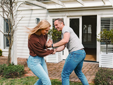 teen daughter and dad playing together outside suburban house entrance