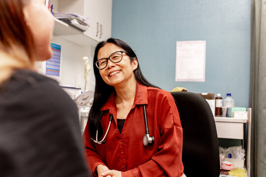Asian otolaryngologist happily talking with a female inside a clinic