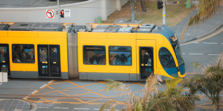 Modern yellow tram with passengers moving through city streets