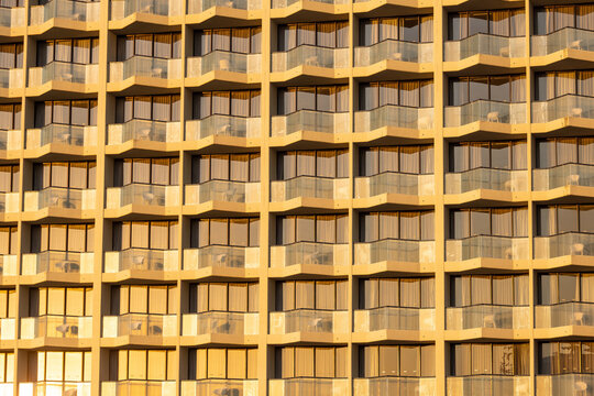 Modern hotel facade with repeating balconies and windows bathed in golden hour light