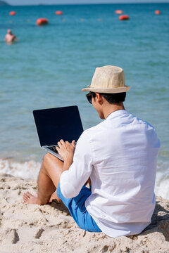 Vertical Man traveler use laptop on summer beach blue sky. Man legs walking on tropical beach. Relaxation Travel footstep. Asian young men wear casual short pants tropical smiling face
