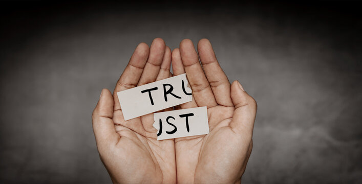 Hands tearing paper with word trust, broken relationship concept, trust issues