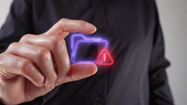 A virtual folder icon and a warning sign. Close-up of a woman's hands holding a virtual folder icon and a warning sign between her two fingers.