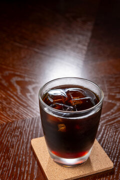 アイスコーヒーがコルクコースターに置かれた木製テーブルの上での一杯