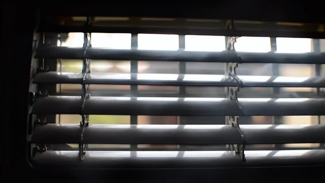 Sunlight streams through the slats of partially closed window blinds, creating bright squares