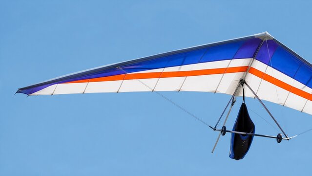 ultralight. A colorful ultralight aircraft wing extended against a clear blue sky. mobility guides, transit brochures, designed for mobility and urban transit guides.