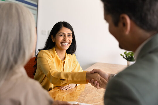 Smiling South Asian applicant shaking hands with HR manager in company office, starting or finalizing job interview. Recruitment process, successful hiring, career opportunity, professional agreement
