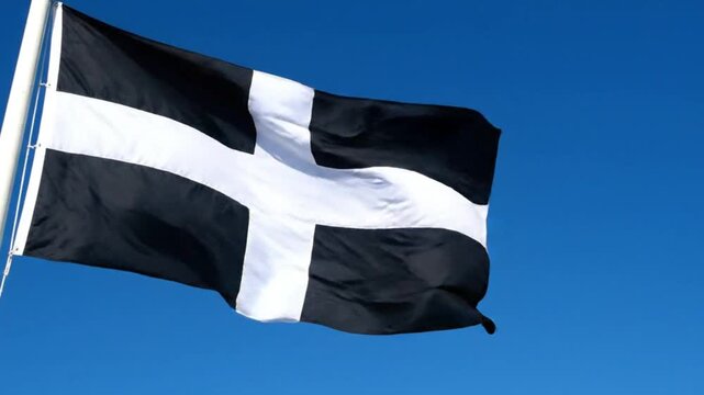 The flag of cornwall, also known as saint pirans flag, waving against a clear blue sky