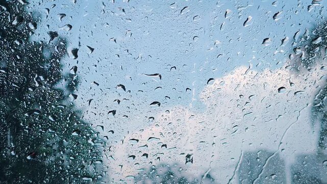 Raindrops dance on the windshield of a car while the wipers occasionally work to wipe away the water, recorded from the atmosphere inside the car. Video transition, 4k, 60 fps