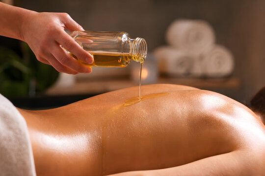 Warm massage oil drizzled onto bare back