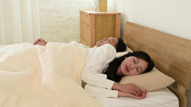 ベッドで寝返りをする日本人夫婦