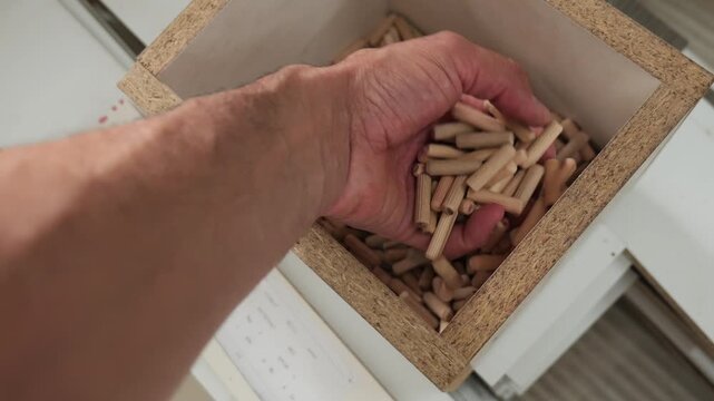 Carpenter taking wooden dowel pins from a box