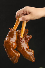 Fototapeta premium Marinated Saucey Cooked Lamb Chops Being Held by Hand with Flavorful Glaze Dripping