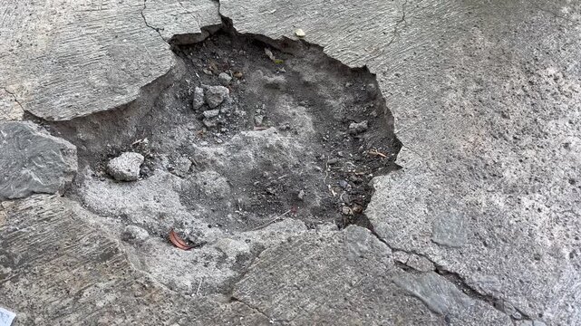 Close up of damaged concrete road with deep pothole