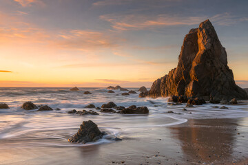Naklejka premium Golden Waves Around Towering Coastal Rock Formations