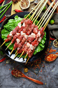 Raw Lamb Kebabs on Skewers Ready for Barbecue Grilling with Asian Spices and Fresh Lettuce Garnish