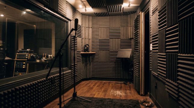 Empty music recording booth with microphone stand removed from focus acoustic foam studio walls interior