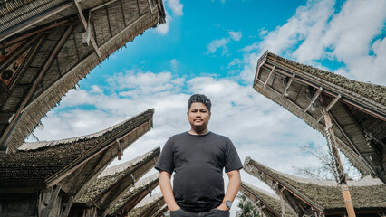 Man stands beneath the traditional Tongkonan roofs of the Torajan ethnic house. © ThomX Design