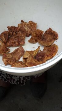 Presentation of a container full of freshly fried crispy pork chicharrones