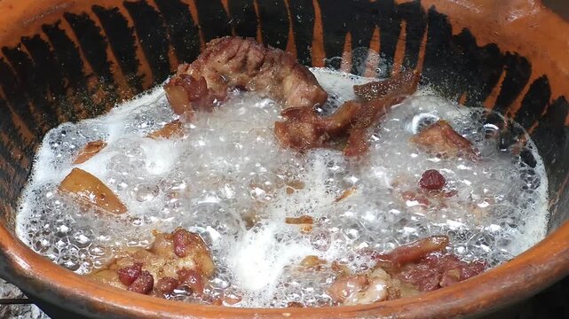 Traditional rendering process of deep frying pork chicharrones in boiling lard