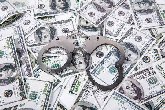 Handcuffs on US Dollar Bills - Financial Crime Concept