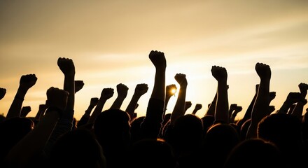 Fototapeta premium Silhouettes of raised fists against sunset sky