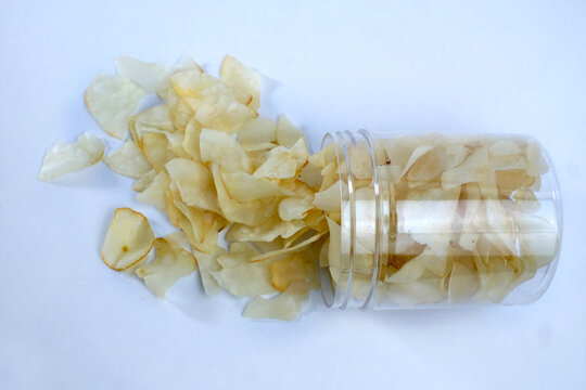 cassava chips or keripik singkong traditional chips from indonesia in an open plastic container, ready to be enjoyed while relaxing, isolated on white background