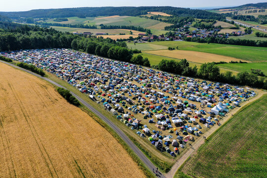 Geiselwind, Germany - 21 June 2025: Aerial view of Eventzentrum Strohofer Geiselwind musichall campsite with hundreds of colorful tents spread across a field near a forest.