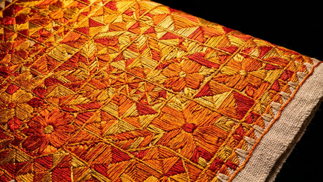 Traditional Phulkari Punjab embroidery macro with dense vivid orange gold red silk thread floral geometric pattern khaddar cotton base on black