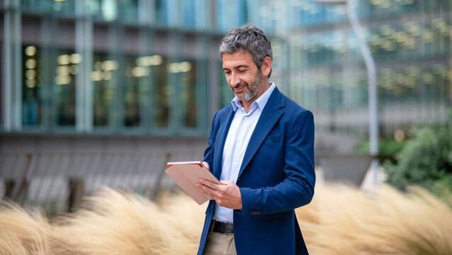 Mature businessman checking tablet in urban environment