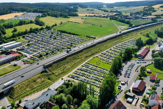 Geiselwind, Germany - 21 June 2025: Aerial view of the Eventzentrum Strohofer Geiselwind musichall with crowded parking lots and traffic on the adjacent highway.
