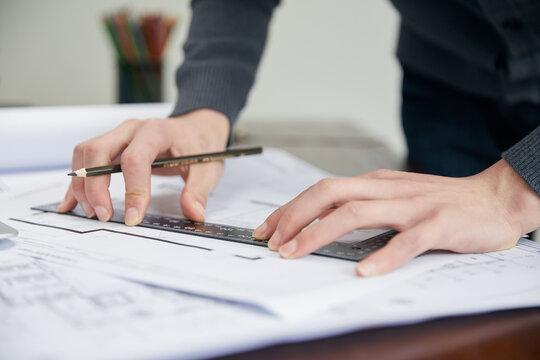 Architect Reviewing Construction Drawings with Ruler and Pencil