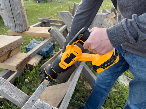 Reciprocating saw cutting rough wood during outdoor demolition work