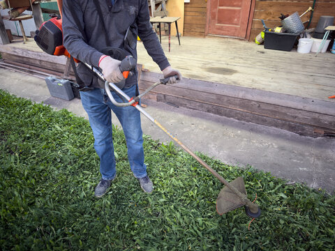 Grass string trimmer cutting weeds in residential backyard garden