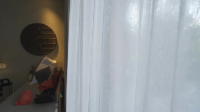 Wind blows the curtain or sways blind in the house or hotel bedroom living room. Sunny day with sun shines through the tulle through the window calm quiet morning curtain texture background.
