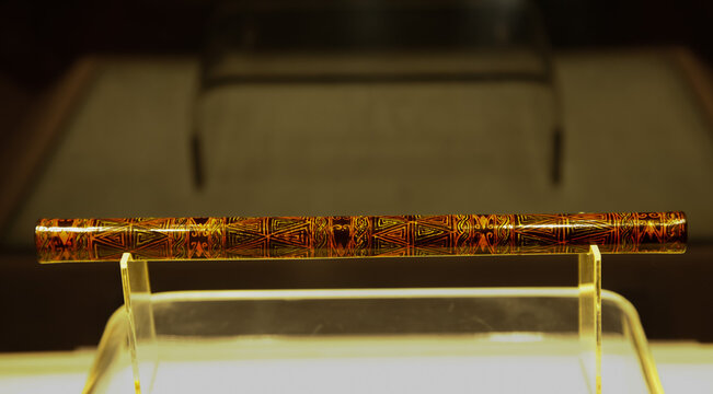Indigenous ceremonial wooden stick with tribal patterns on museum display stand - cultural heritage artifact collection