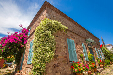 Ayvalik - Turkey, May 17, 2026, Historic Stone Mansion with Blue Shutters and Jasmine Flowers on Cunda Island © Esin Deniz