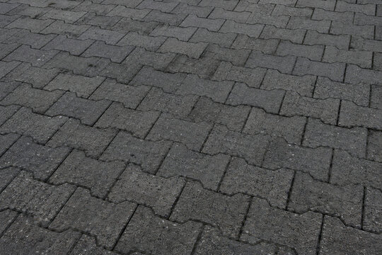 Dark gray interlocking concrete paving stones for urban sidewalk texture background
