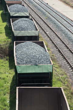 Vertical overhead view of freight wagons carrying ballast gravel near reconstructed railway tracks and rail infrastructure.