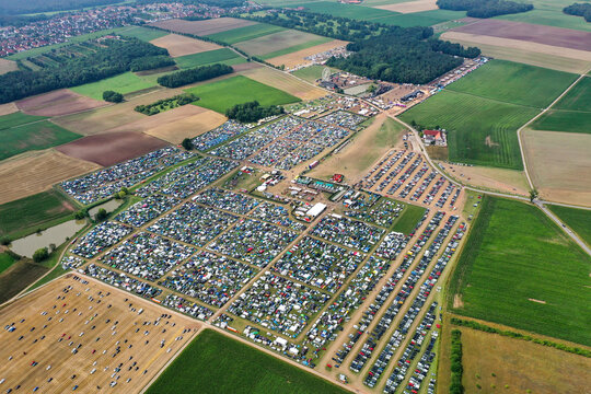 Herzogenaurach, Germany - 26 July 2025: Aerial view of Open Beatz Festival featuring a large campsite with tents, a Ferris wheel, and parking areas surrounded by green fields.