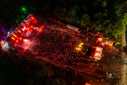 Herzogenaurach, Germany - 26 July 2025: Aerial view of Open Beatz Festival featuring an illuminated main stage with red lights, a large crowd of people, and white tents at night.