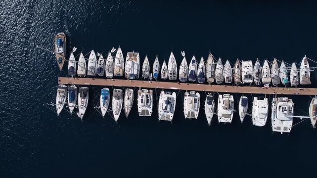 Aerial yacht row revealing sleek decks and hulls, polished surfaces catching sunlight, mooring cleats and fenders visible, luxurious textures and craftsmanship emphasized, ideal for luxury charter